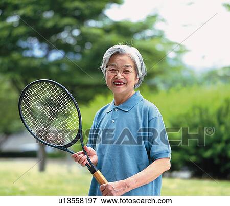 Stock Photo - Senior adult woman holding a tennis racket, Front View. Fotosearch