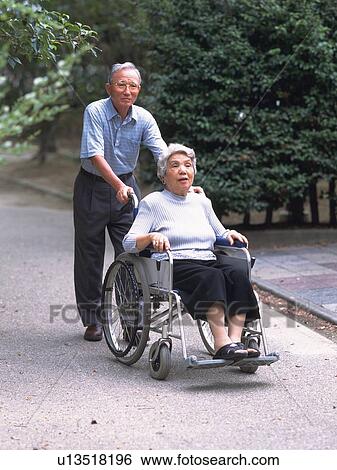 Senior adult woman on a wheelchair and her husband pushing it, Front View View Large Photo Image Stock Photograph - Senior adult woman on a wheelchair and her husband pushing it, Front View. Fotosearch