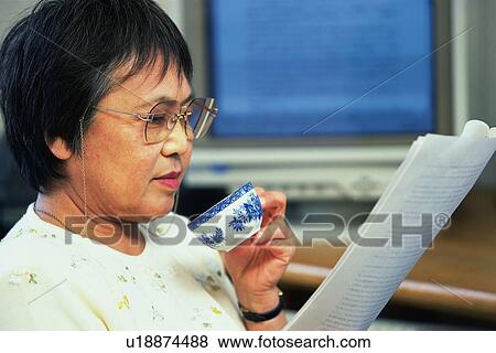 Senior adult woman reading documents with a cup in hand, Side View View Large Photo Image Stock Photo - Senior adult woman reading documents with a cup in hand, Side View. Fotosearch