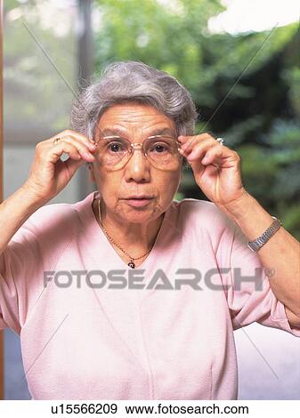 Stock Photo - Senior adult woman smiling with Glasses in hand, Front View. Fotosearch