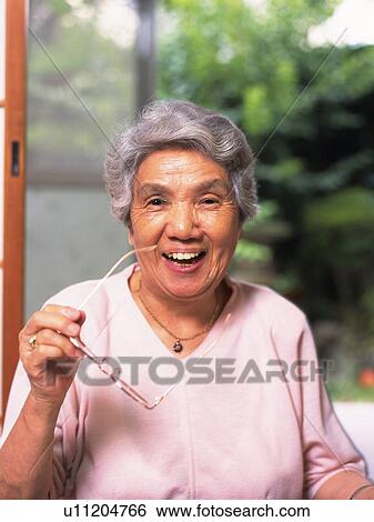 Stock Photograph - Senior adult woman smiling with Glasses in hand, Front View. Fotosearch