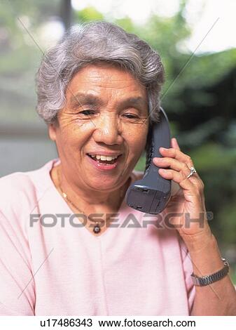 Stock Image - Senior adult woman talking on the phone, Front View. Fotosearch