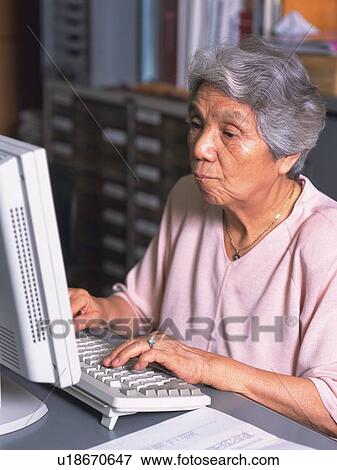 Stock Photo - Senior adult woman using a computer, High Angle View. Fotosearch