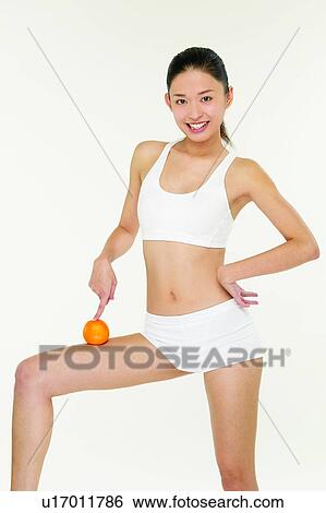 Stock Photograph - Orange, Toothy Smile, Lifestyles, One Person, Sports Bra, Apple. Fotosearch