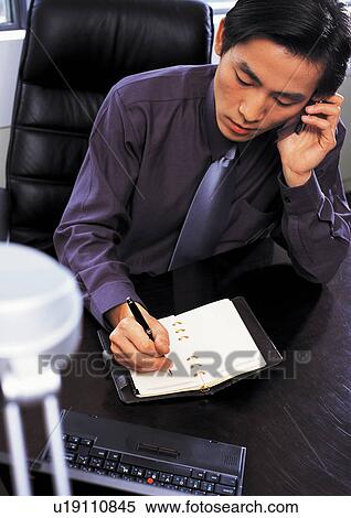 Stock Photography - listening, asian ethnicity, diary, profession, writing, purple shirt, sitting. Fotosearch