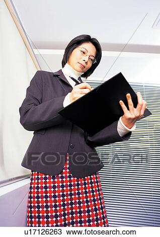 Stock Image - well dressed, reading, business in asia, asian ethnicity. Fotosearch