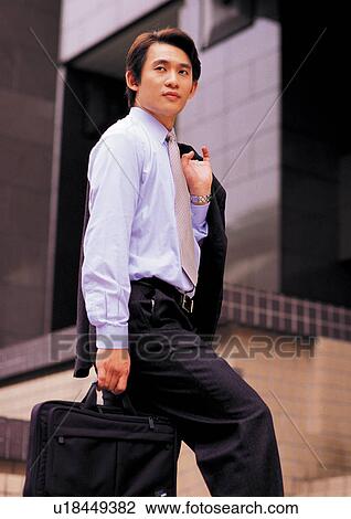 Stock Image - well dressed, suit, holding coat, one person, black hair. Fotosearch