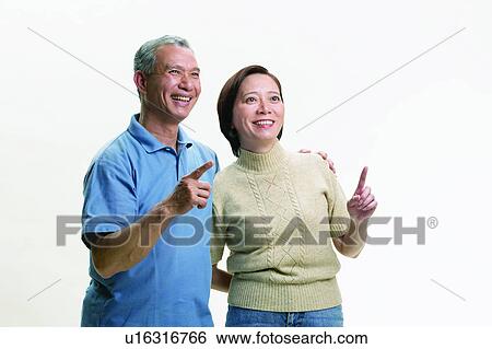 Stock Photograph - Heterosexual Couple, Standing, Two People, Gray Hair, Pointing, Mature Men, Close-Up. Fotosearch