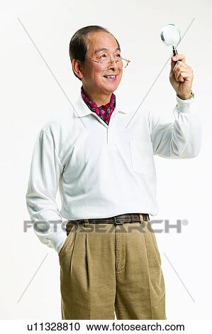 Stock Image - Standing, Holding, Polo Shirt, Asian Ethnicity, Balding, Casual Clothing, Magnifying Glass. Fotosearch