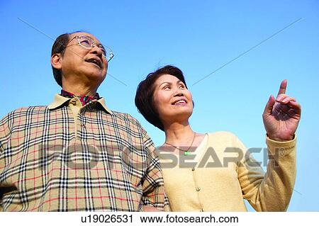 Stock Image - Waist-Up, Bonding, Pointing, Asian Ethnicity, Casual Clothing, Close-Up. Fotosearch
