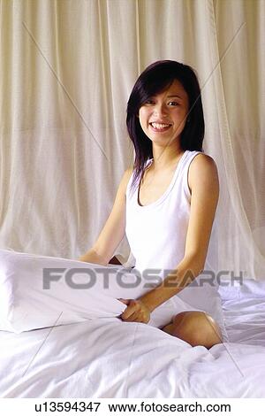 Stock Photo - Bed, Brown Hair, Bedroom, Asian Ethnicity. Fotosearch