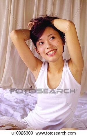 Stock Photo - Close-Up, Asian Ethnicity, Brown Hair, Bedroom, Bed, Arms Raised. Fotosearch