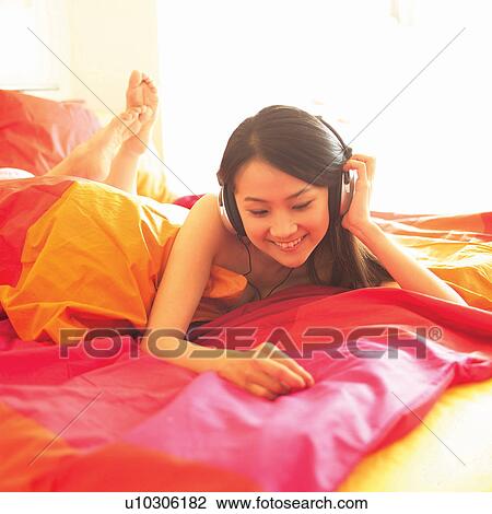 Stock Image - Barefoot, Brown Hair, Bedroom, Bed, Asian Ethnicity. Fotosearch