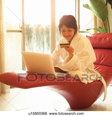 Stock Photo - Home Shopping, One Young Woman Only, Couch, Home Interior, Tiled Floor, Young Adult, Business. Fotosearch