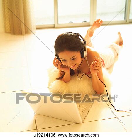 Stock Photograph - Music, Brown Hair, Relaxation, Tank Top, Tiled Floor, Headphones, Pedal Pushers. Fotosearch