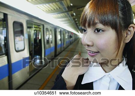 Stock Image - Brown Hair, Focus On Foreground, Railroad Station Platform, Day, Head And Shoulders, Office Lady. Fotosearch