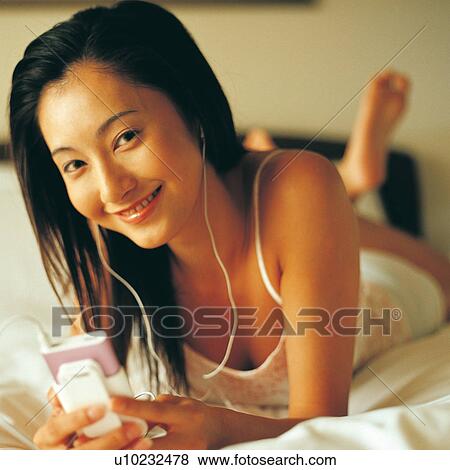 Stock Photo - Bedroom, Asian, Bed, Barefoot, MP3 Player, Asian Ethnicity. Fotosearch