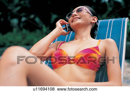 Stock Photo - Asian, Black Hair, Bikini, On the Phone, Asian Ethnicity. Fotosearch