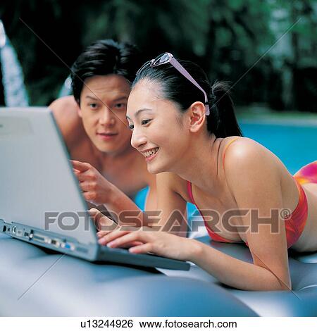 Stock Photograph - Vacations, Swimming Pool, Outdoor, Waist-Up, Wireless Technology, Young Men, Leaning. Fotosearch