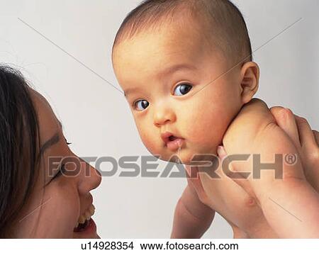 Picture - Baby boy is lifted by mother, portrait, side view. Fotosearch