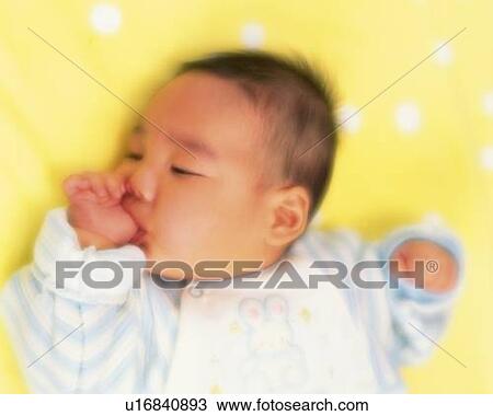 Stock Image - Baby boy lying on bed, High Angle View, Defocused, portrait. Fotosearch