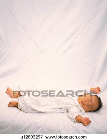 Stock Photo - Baby boy lying on bed, high angle view, portrait. Fotosearch