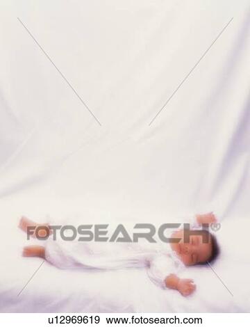 Stock Photo - Baby boy lying on bed, high angle view, defocused, portrait. Fotosearch