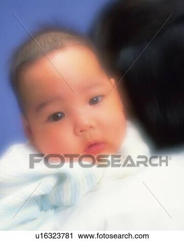 Stock Image - Baby boy smiling on mother's shoulder, defocused, portrait. Fotosearch