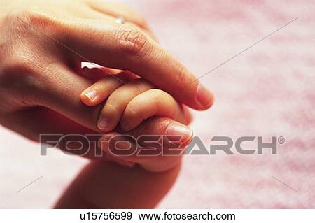 Stock Photo - Baby holding mother's finger, close up, high angle view . Fotosearch