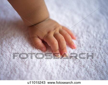 Stock Image - Baby's left hand, high angle view. Fotosearch