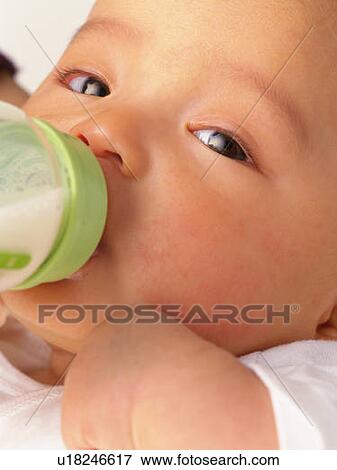Stock Photo - Close up of baby boy drinking milk, portrait, side view. Fotosearch