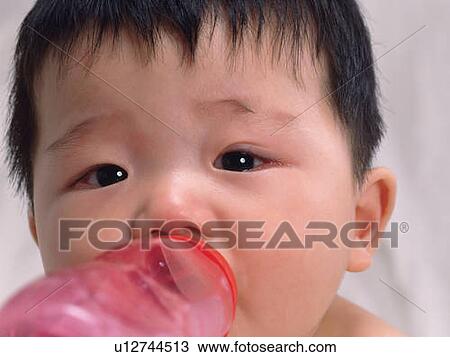 Stock Image - Close up of baby's face, drinking milk, front view, portrait, Full Frame . Fotosearch