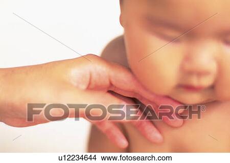 Picture - Close up of mother's hand touching baby face, high angle view, Differential Focus. Fotosearch