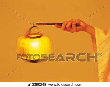 Stock Photo - A hand of woman in yukata holding a Japanese lantern, Close Up, Side View, Blurred Motion, Toned Image. Fotosearch