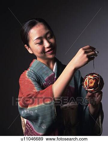 Stock Photo - A woman in kimono holding a temari ball, Front View. Fotosearch
