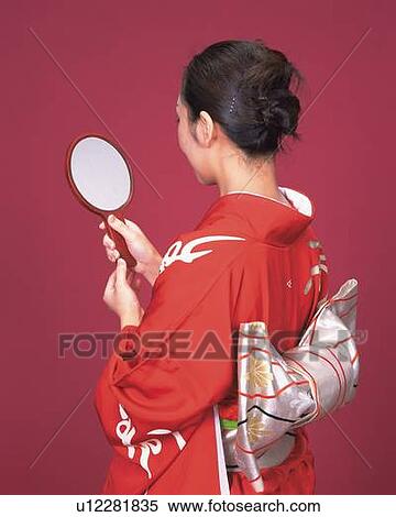 Stock Photography - A woman in kimono looking into mirror, Rear View. Fotosearch