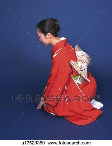 Stock Image - A woman in kimono sitting and bowing, High Angle View, Side View. Fotosearch