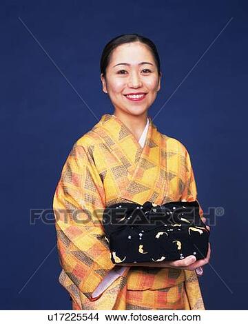 A woman in kimono smiling and holding a gift, Front View View Large Photo Image Picture - A woman in kimono smiling and holding a gift, Front View. Fotosearch