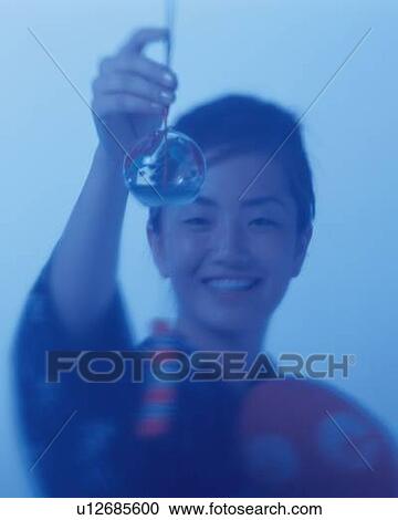 A woman in kimono smiling and holding a Japanese wind bell in hand, Differential Focus, Toned Image, Front View View Large Photo Image Stock Image - A woman in kimono smiling and holding a Japanese wind bell in hand, Differential Focus, Toned Image, Front View. Fotosearch