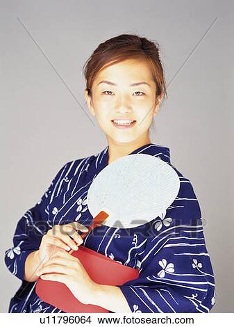A woman in yukata smiling and holding a Japanese fan, Front View View Large Photo Image Picture - A woman in yukata smiling and holding a Japanese fan, Front View. Fotosearch
