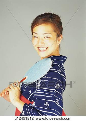 A woman in yukata smiling and holding a Japanese fan, Side View View Large Photo Image Stock Image - A woman in yukata smiling and holding a Japanese fan, Side View. Fotosearch