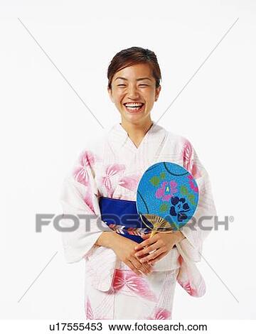 Stock Image - A woman in yukata smiling and holding a fan, Front View. Fotosearch