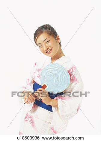 Stock Photograph - A woman in yukata smiling and holding a Japanese fan, Front View. Fotosearch