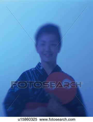 Stock Photography - A woman in yukata smiling and holding a fan, Front View, Soft Focus, Toned Image. Fotosearch