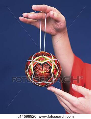 Stock Image - Hands holding a temari ball, Close Up. Fotosearch