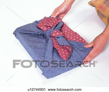 Stock Image - Hands of a woman in kimono holding a wrapped gift, Close Up, High Angle View. Fotosearch
