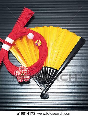 Stock Image - Bunch of red strings on Japanese folding fan, high angle view. Fotosearch