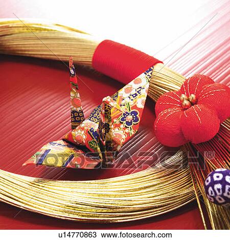 Stock Image - Origami bird in circle of bunch of gold strings, high angle view. Fotosearch