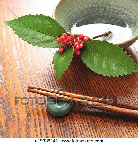 Stock Image - Plant with red berries in a bowl and chopsticks on holder, high angle view. Fotosearch