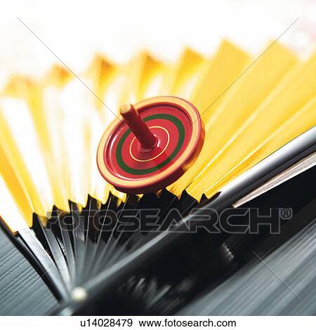 Stock Photo - Spinning top on Japanese folding fan, high angle view, differential focus. Fotosearch